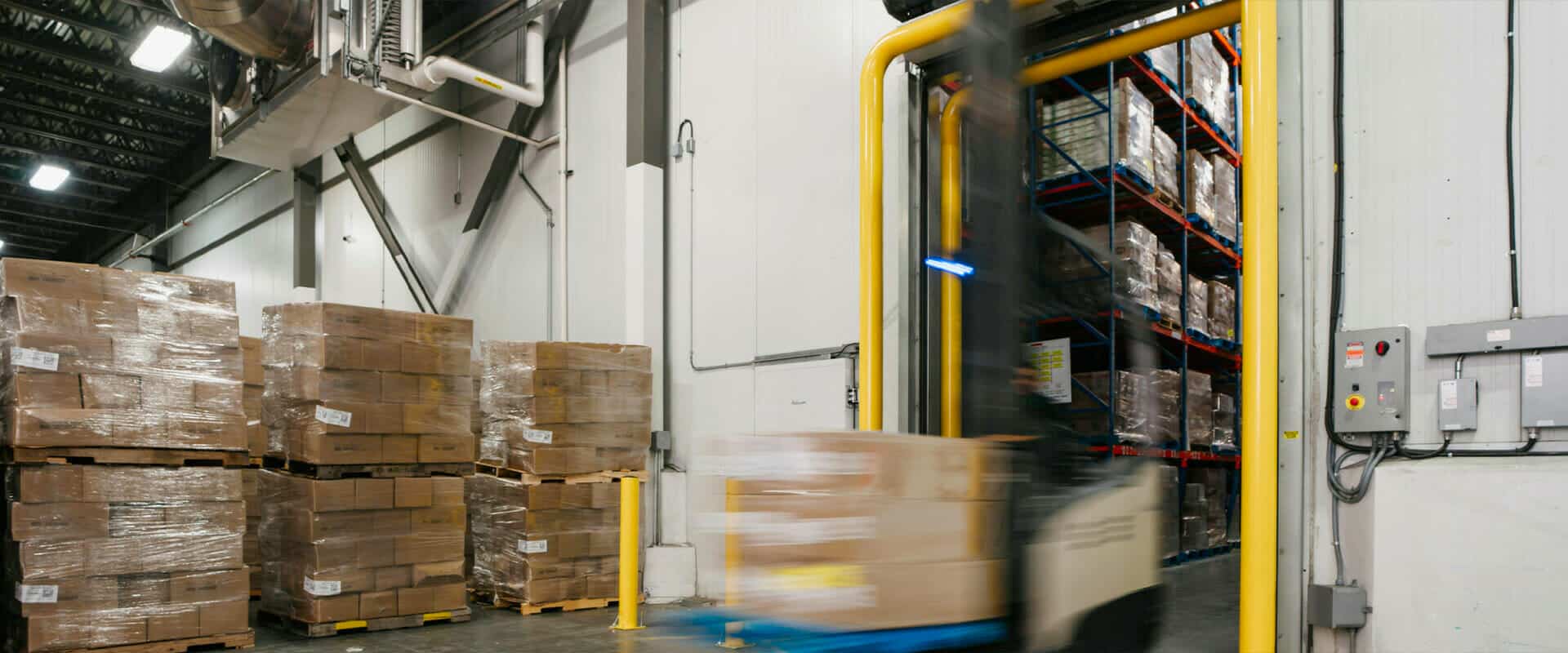 In a warehouse, a palette of frozen food items is being transported from one location to another