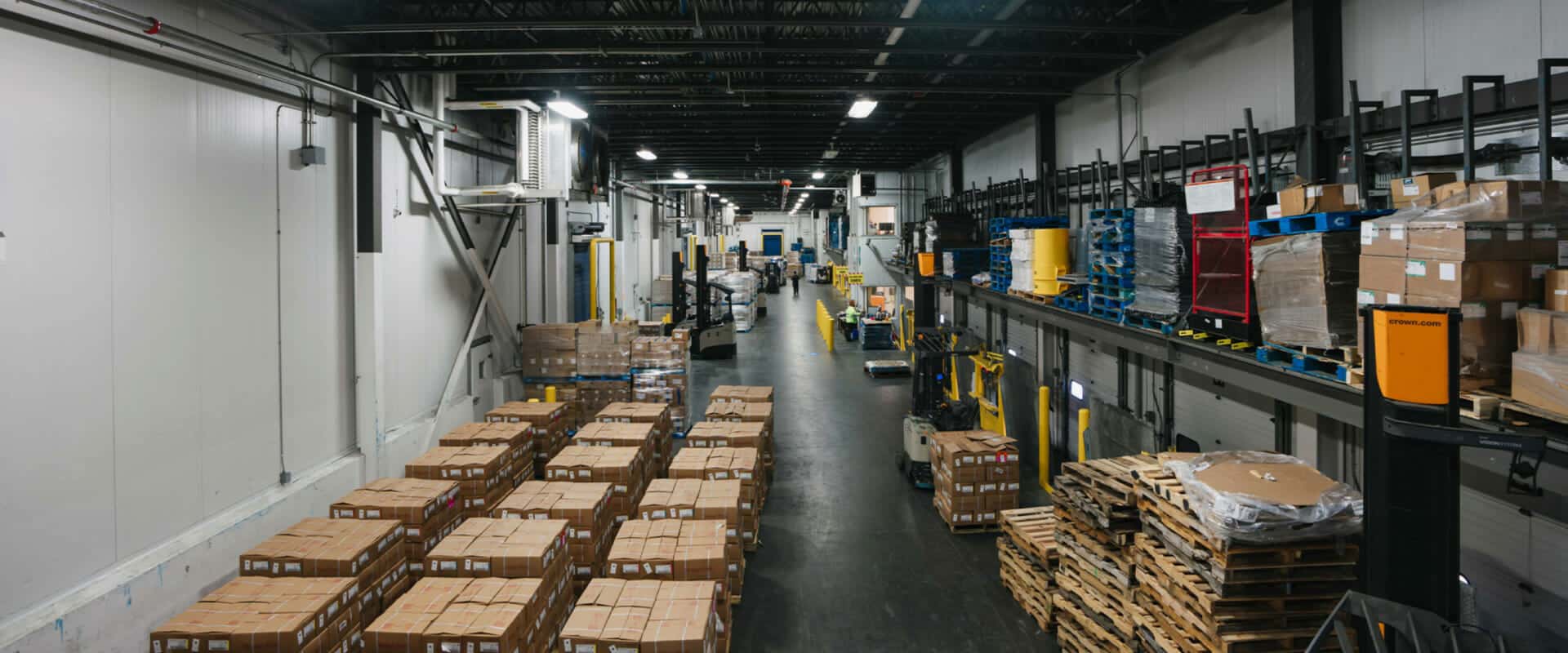 A large warehouse with boxes, and empty palettes
