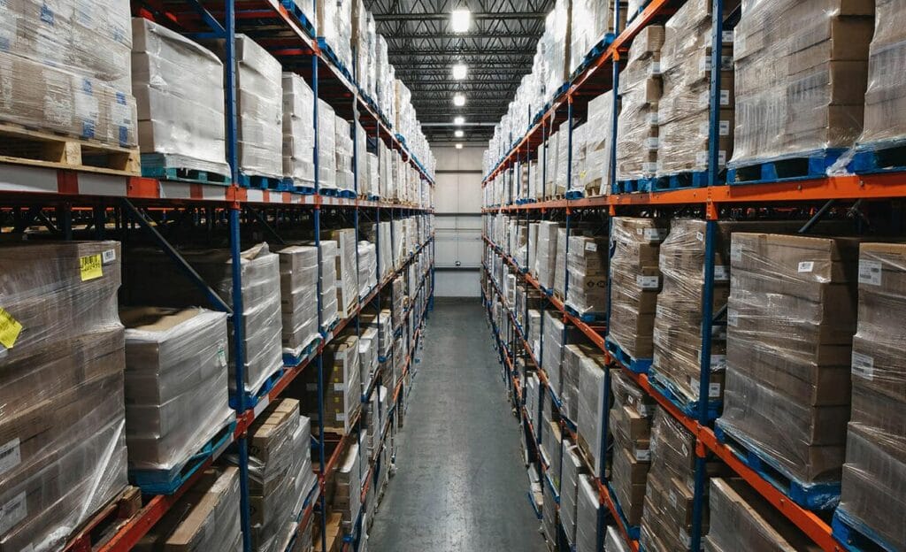 Looking down an isle of a large warehouse with palettes from ground to ceiling