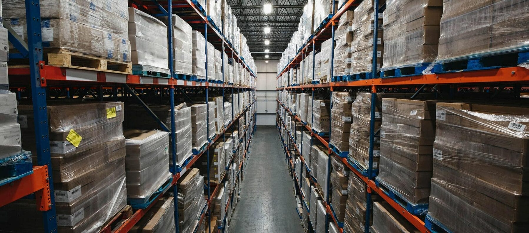 Looking down an isle of a large warehouse with palettes from ground to ceiling